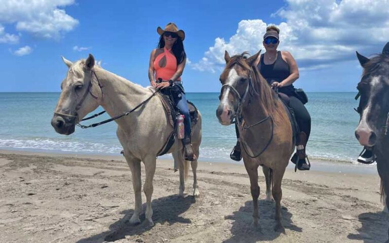 two women on horseback on the beach at tours on horseback fort pierce