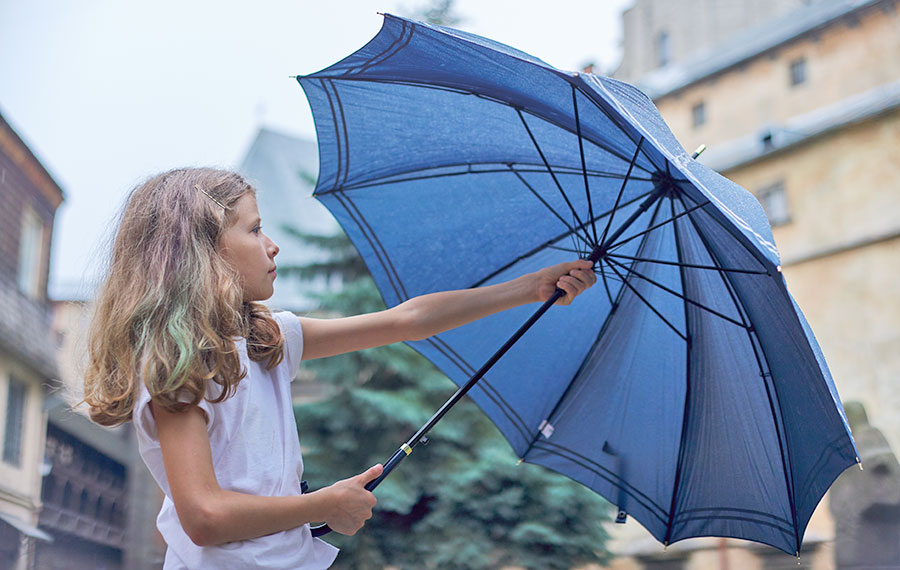 young girl opening blue umbrella as rain starts to fall