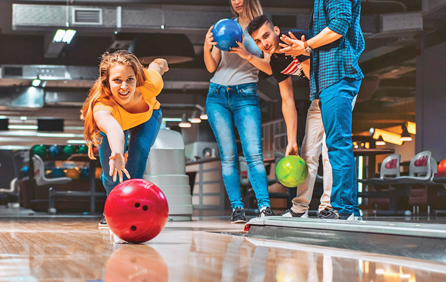 young lady bowling beside friends in alley at bowlero west ocala