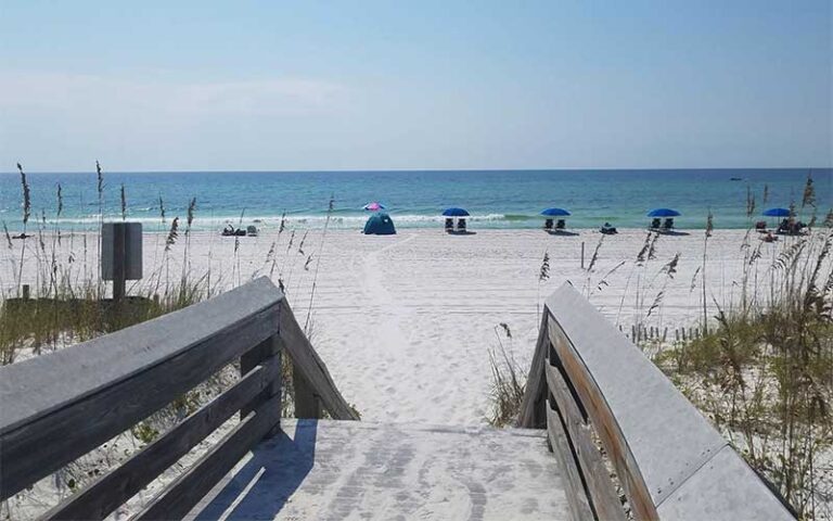 boardwalk leading to beach with row of umbrellas and loungers at john beasley park fort walton beach