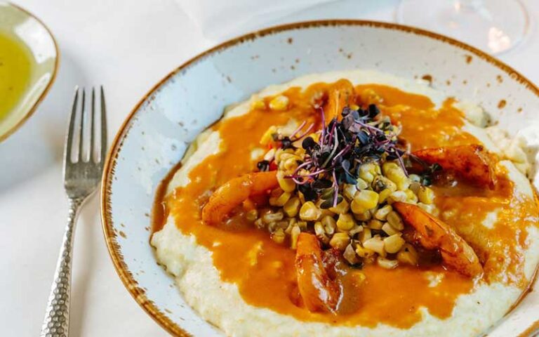 cajun shrimp grits entree with table setting at cafe thirty a santa rosa beach