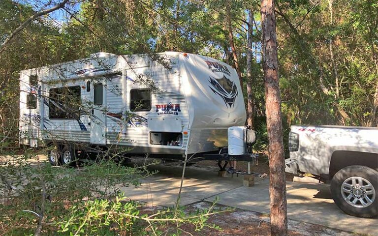 camper trailer with truck on rv pad in woods at topsail hill preserve state park santa rosa beach