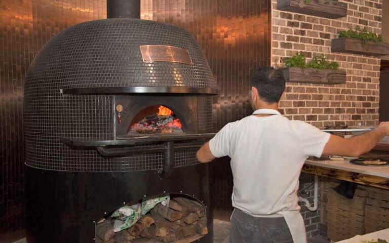 chef putting pizza in wood fired oven at pazzo italiano destin