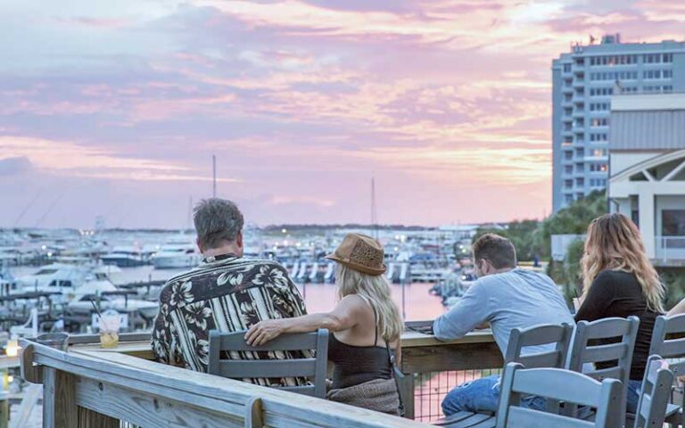couples seated on patio overlooking harbor with twilight sky at boshamps seafood oyster house destin