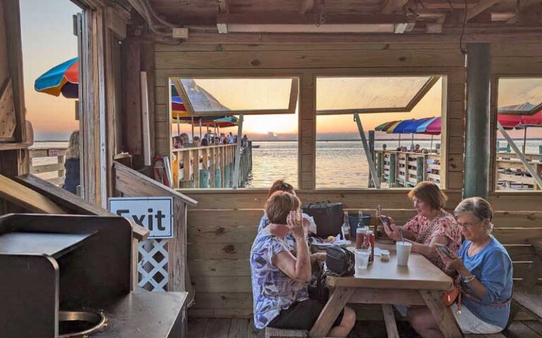 diners seated along pier with sunset view at dewey destins seafood restaurant