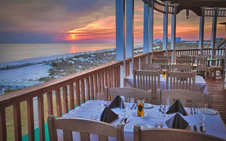 dining area with tables along veranda overlooking sunset over gulf at henderson beach resort destin