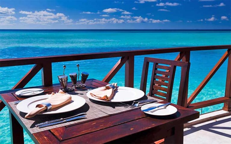 dining seating along rail over blue water at stuart boathouse