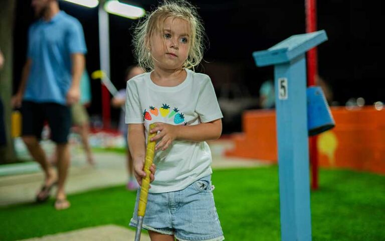 girl playing mini golf at night at goofy golf fort walton beach