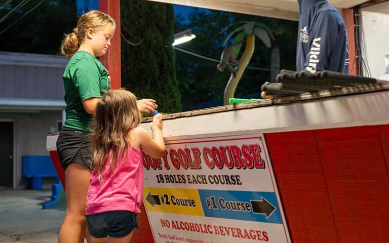 girls paying at booth for putting at goofy golf fort walton beach