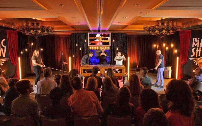illusionist act on small stage with volunteers at the magic show at grande lakes orlando