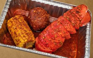 lobster tail boil with corn and potato in tray at outcast seafood miramar beach
