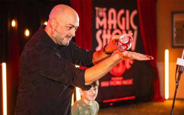 magician holding up crushed soda can with boy looking at the magic show at grande lakes orlando
