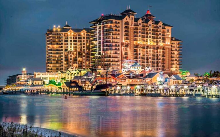 night view across water of lighted complex with hotel towers at emerald grande at harborwalk village destin