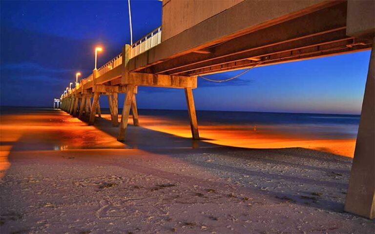 night view from under lighted pier on beach at okaloosa island pier