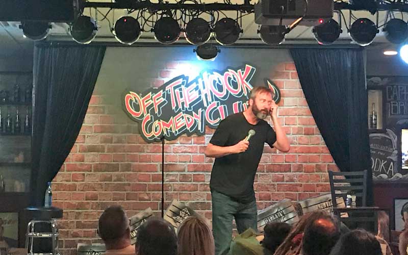 stand up comedian performing on dais at off the hook comedy club naples