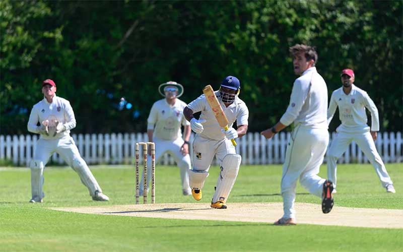 cricket team playing on green field with white uniforms at miramar match