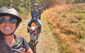 woman taking selfie of horseback riders along field trail at rock springs guest ranch sorrento