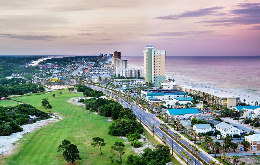 aerial view of coastline and streets with high rise buildings and purple sky at panama city beach