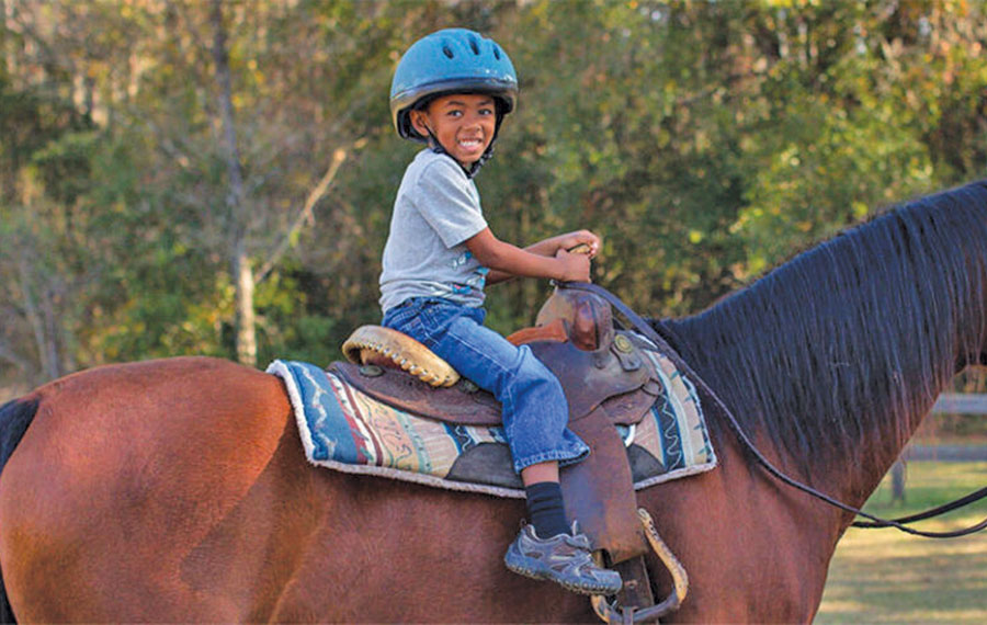 boy with helmet on horseback at rock springs guest ranch