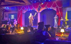 diners seated around stage with performer at speakeasy murder teatro martini