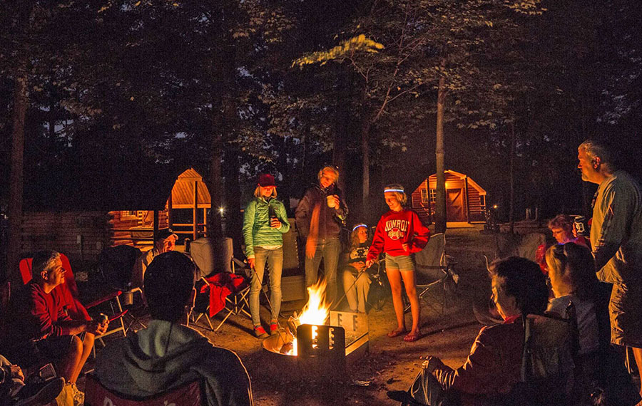 family enjoying campfire at campsite with cabins and woods at lion country safari koa west palm beach