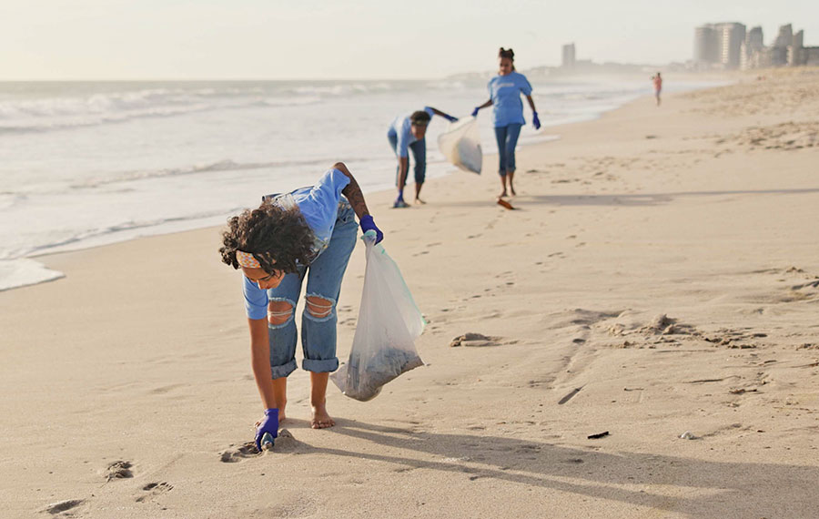family picking up trash along beach
