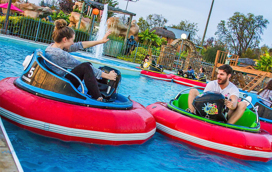 man and woman in separate bumper boats splashing each other at the track destin
