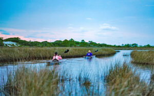 two kayakers paddling through marshy inlet at get up and go kayaking destin