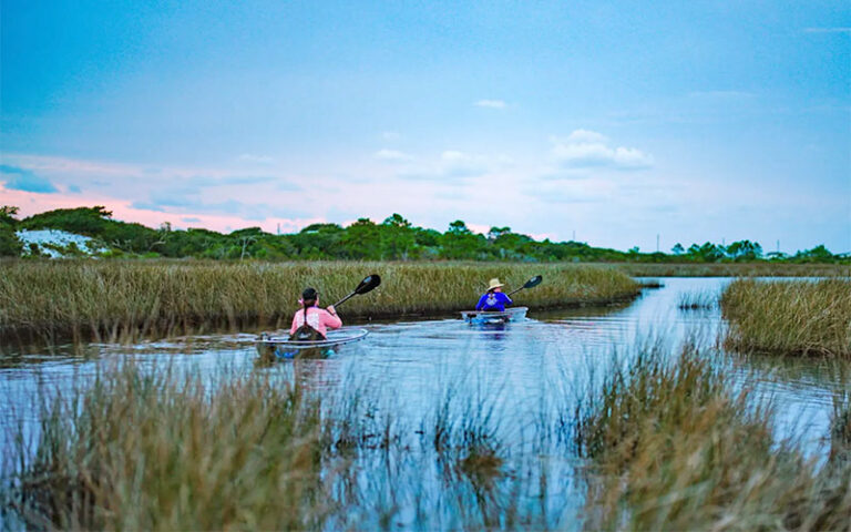 two kayakers paddling through marshy inlet at get up and go kayaking destin