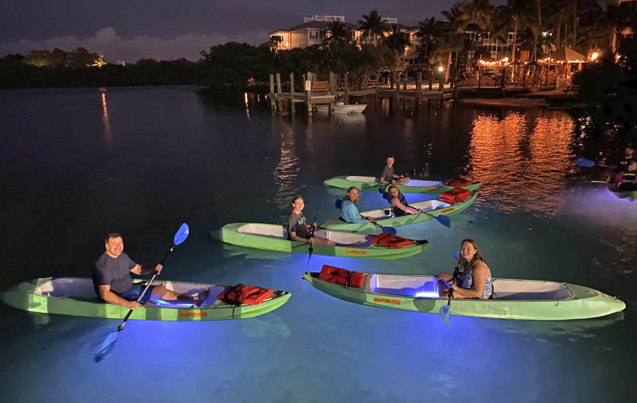 family in lighted kayaks on dark bay at night kayak key west