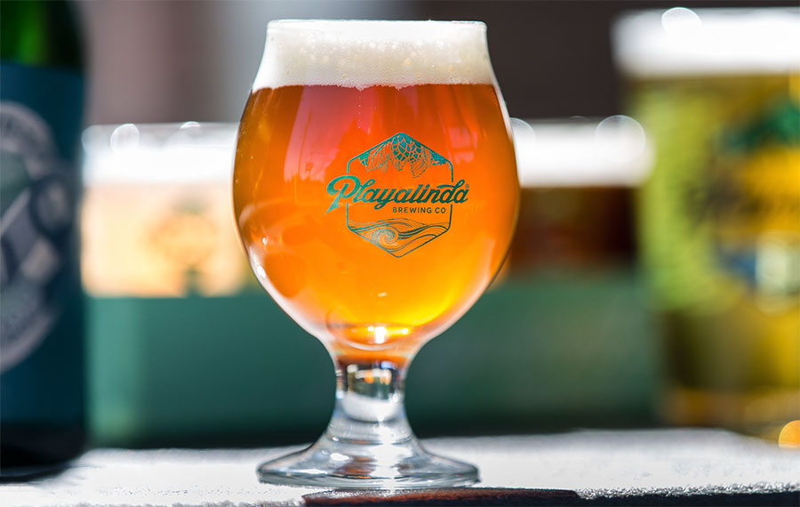 pint glass with amber beer on bar with blue logo on glass at playalinda brewing company