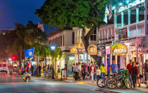 rows of lighted shops and cafes along duval street at night in key west