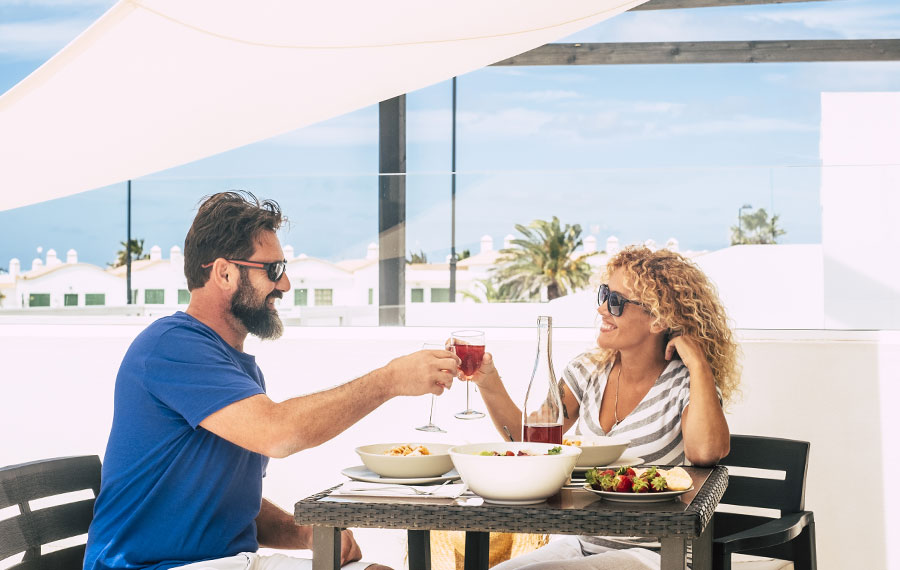 florida couple toasting wine seated in patio restaurant with sun shade