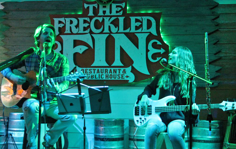 man and woman singing with guitars on stage at freckled fin irish pub holmes beach anna maria island