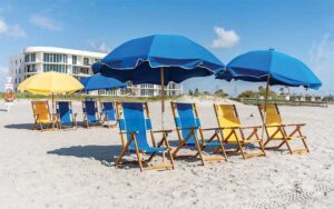 rows of blue and yellow umbrellas and chairs at beach shack rentals cocoa beach