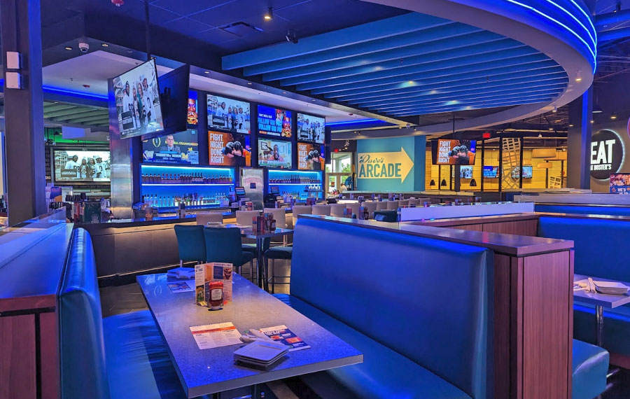booths and bar dining area with blue neon lighting at dave busters fort myers