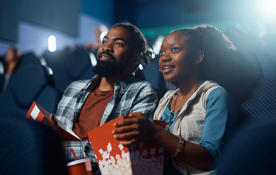 couple watching movie with popcorn in dim theater