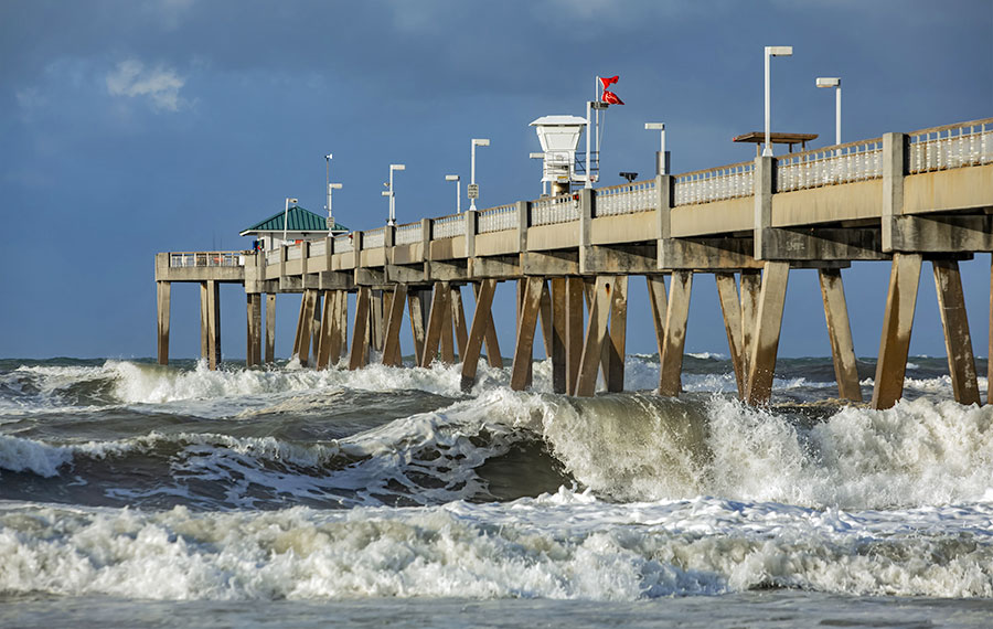 view from shore of okaloosa pier with rough surf and clouds at fort walton beach destin
