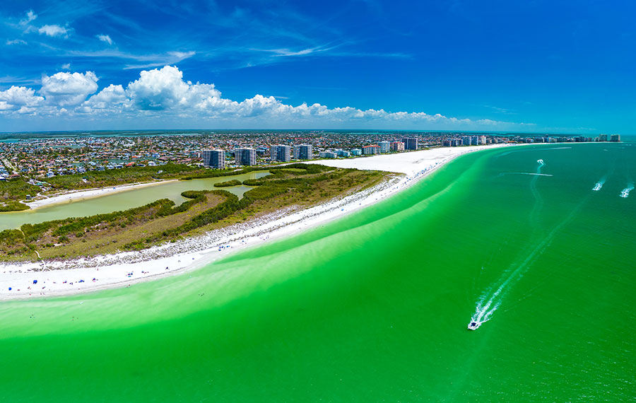 aerial view of island beach and intracoastal with green gulf water and boats at marco island naples