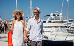 happy couple strolling along dock with yachts