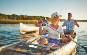 laughing young woman canoeing with man on river