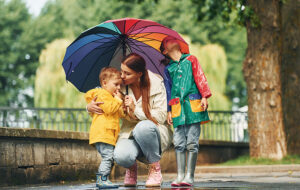 mother with her little son and daughter under umbrella in park