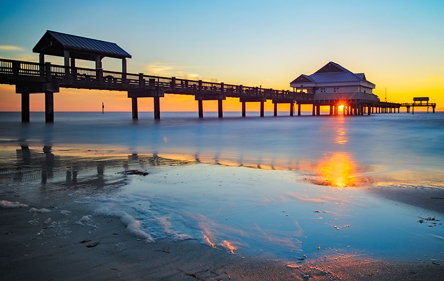 view from beach with reflective surf of sunset through pier structure at pier 60 clearwater