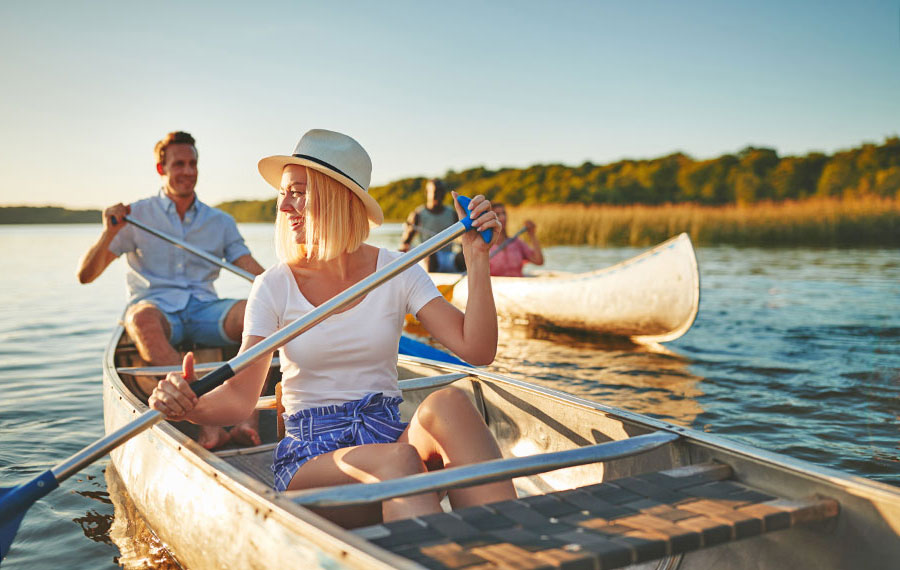 laughing young woman canoeing on a lake with man on river