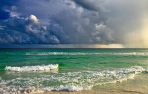 green surf on beach with dark storm clouds in sky destin