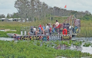 sideview of airboat with passengers on swampy area at crazy golf airboat tours kissimmee st cloud