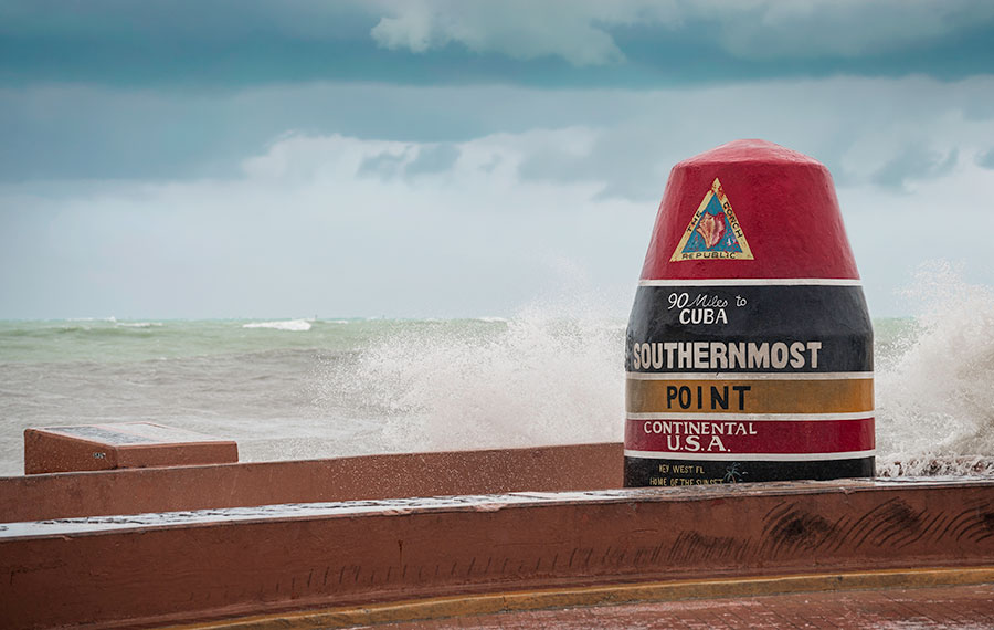 southernmost point marker with storm clouds and ocean key west