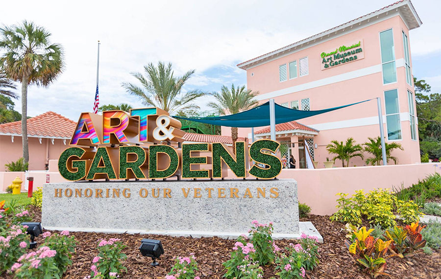 outdoor sign with flowers and building at ormond memorial art museum gardens